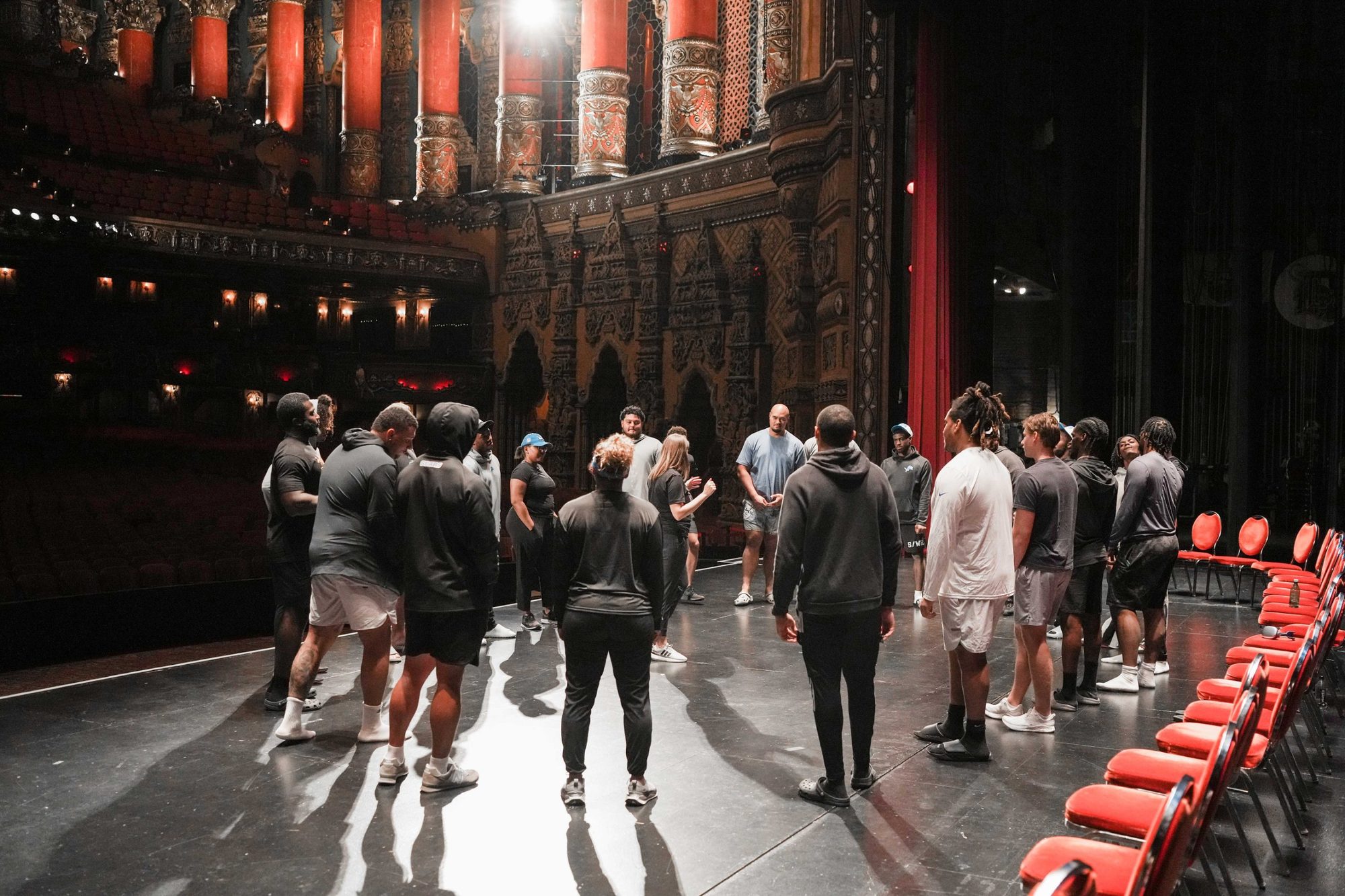 Players standing in a circle on a theater stage during a Rookie Development Lab, with Lainie Hodges leading.