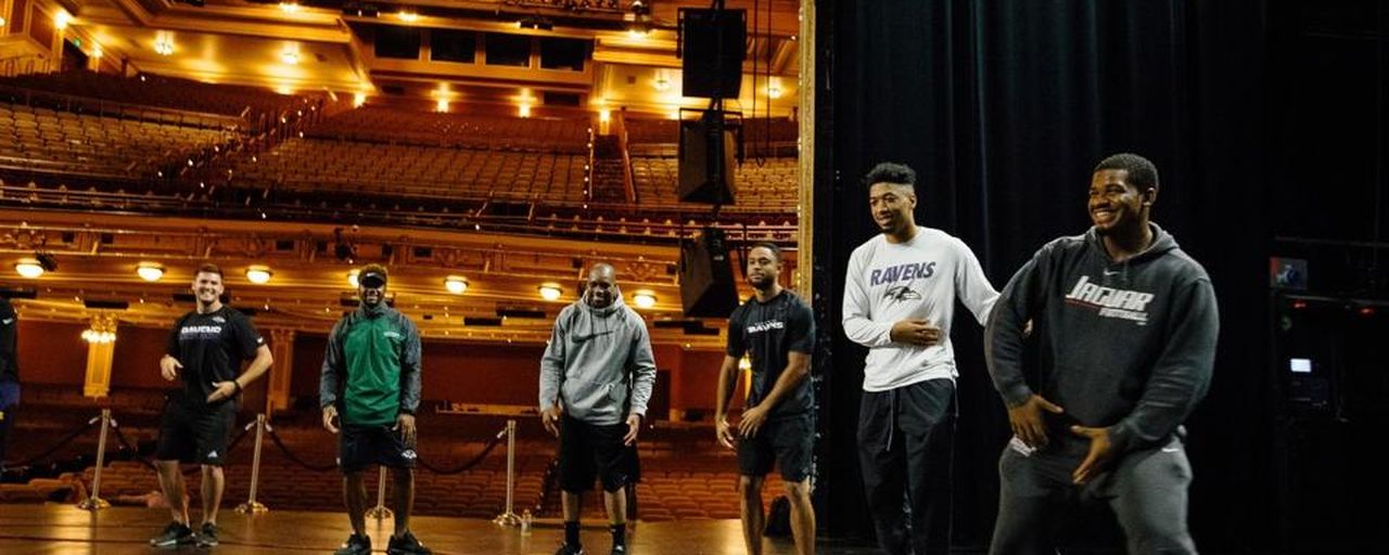Players smiling on a theater stage during a session.